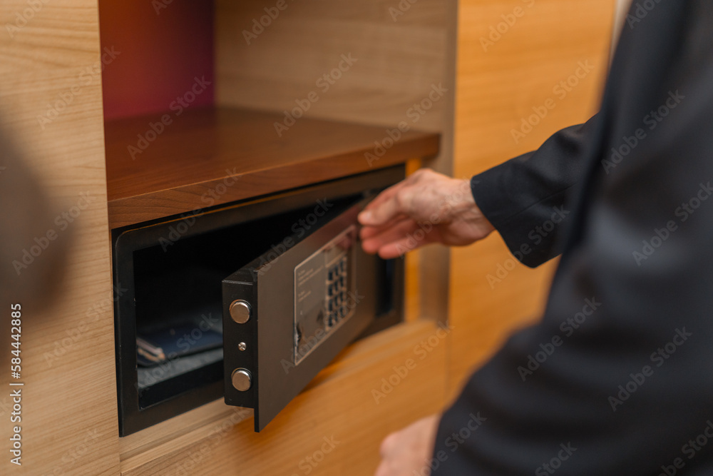 A hand enters a code to open and lock a safe or safe in a hotel room