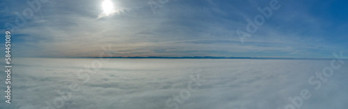 Aerial view from high altitude of earth covered with white puffy cumulus clouds on sunny day © bilanol