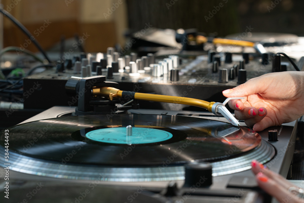 Obraz premium Female DJ playing mixing music on vinyl turntables at party
