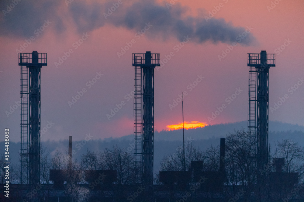 Smoke from the chimneys at the plant against the backdrop of the sunset.