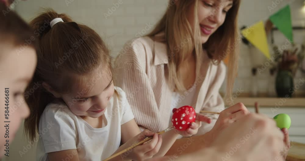 Joyful family painting Easter eggs together at the table in bright modern kitchen. Family gathering in preparation for Easter. Close-up shot. Joyful family painting Easter eggs together at the table in bright modern kitchen. Family gathering in preparation for Easter. Close-up shot.