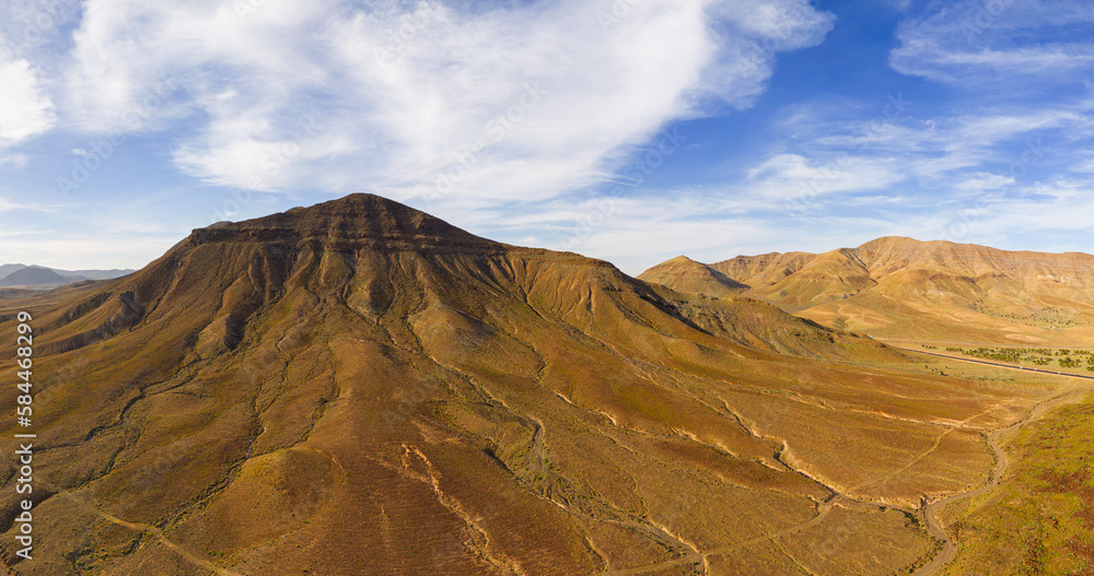Naklejka premium Awesome high level aspect panoramic view of the dramatic volcanic mountains and rocky landscape in the late afternoon sun on the island of Fuerteventura in the Canary Islands Spain