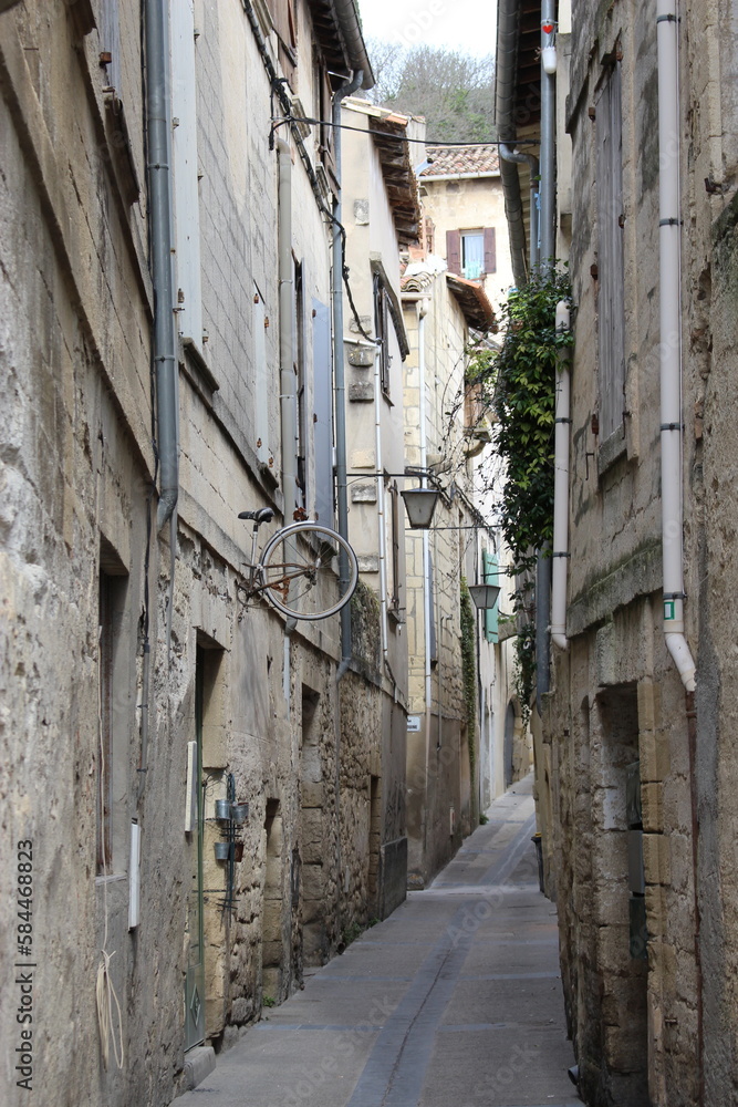 A typical, ancient, narrow stone street in a small French town in Occitania, Sommières. Passageway seen in winter
