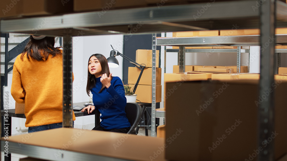 Team of asian workers using laptop to plan shipment, checking quality of goods in warehouse. Depot employees packing products in boxes for order management, financial planning. Team of asian workers using laptop to plan shipment, checking quality of goods in warehouse. Depot employees packing products in boxes for order management, financial planning.