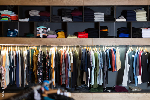Men clothing shop, assorted casual clothes on hangers and shelves in garments store