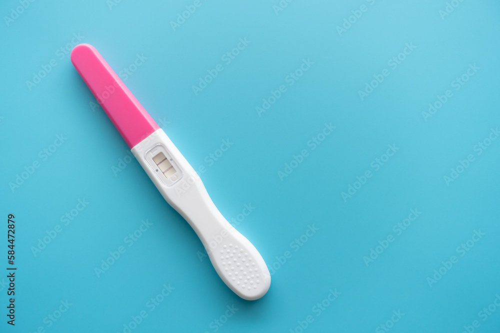 White Plastic Pregnancy test positive with two stripes results isolated on Pastel light blue background. Closeup. Top down view. White Plastic Pregnancy test positive with two stripes results isolated on Pastel light blue background. Closeup. Top down view.