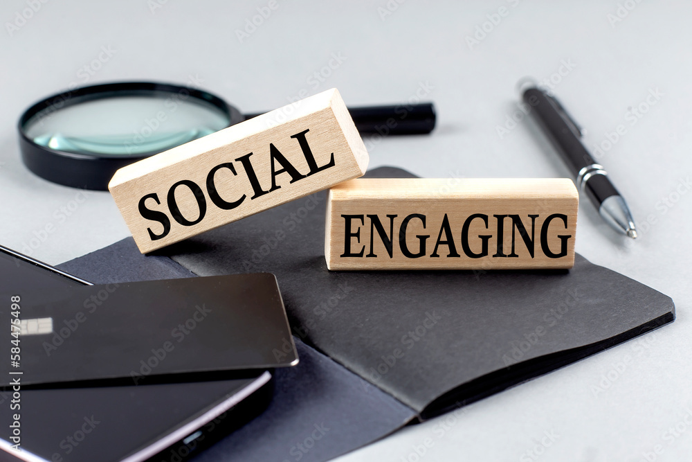 Fototapeta premium SOCIAL ENGAGING text on wooden block on black notebook , business concept