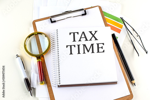 TAX TIME text on notebook with clipboard on white background photo