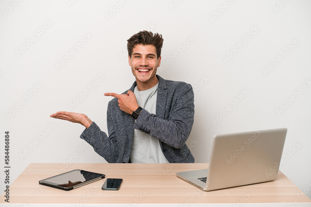 Young entrepreneur man working with a laptop isolated excited holding a copy space on palm. Young entrepreneur man working with a laptop isolated excited holding a copy space on palm.