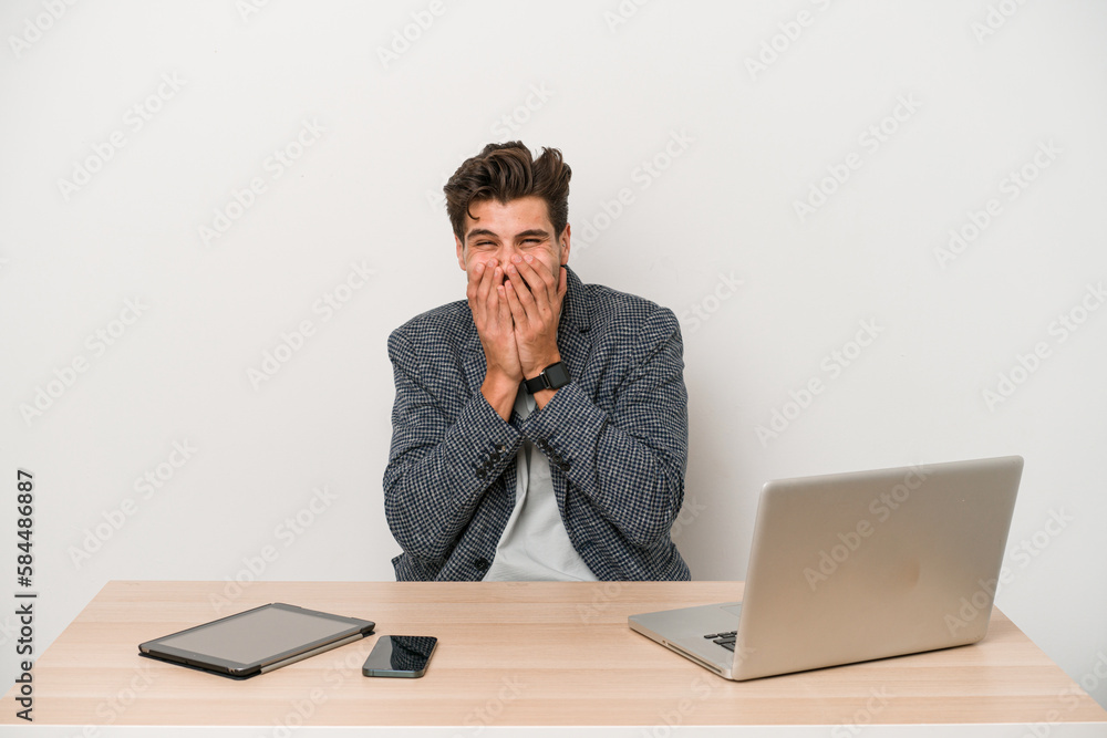 Young entrepreneur man working with a laptop isolated laughing about something, covering mouth with hands. Young entrepreneur man working with a laptop isolated laughing about something, covering mouth with hands.