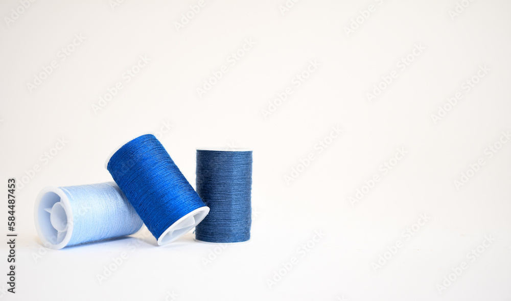 Three spools of blue yarn in different shades on a white background. Copy space Three spools of blue yarn in different shades on a white background. Copy space