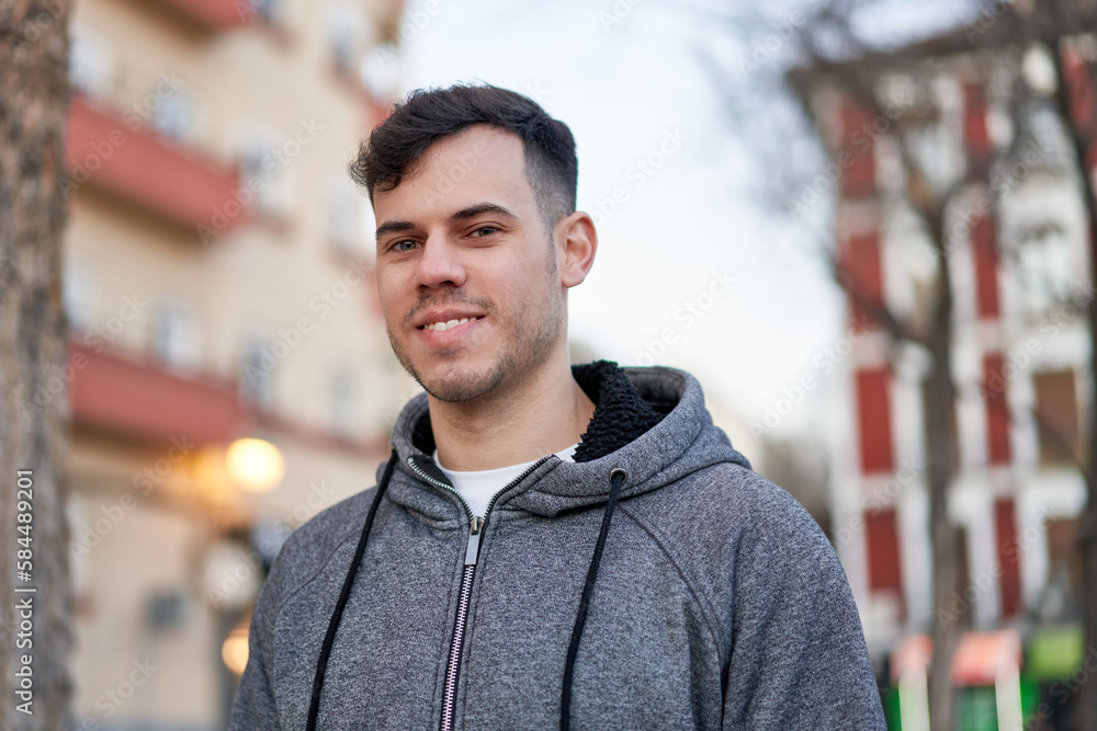 Young caucasian man smiles under the city lights, enjoying the vibrant night atmosphere on the urban street. Young caucasian man smiles under the city lights, enjoying the vibrant night atmosphere on the urban street.