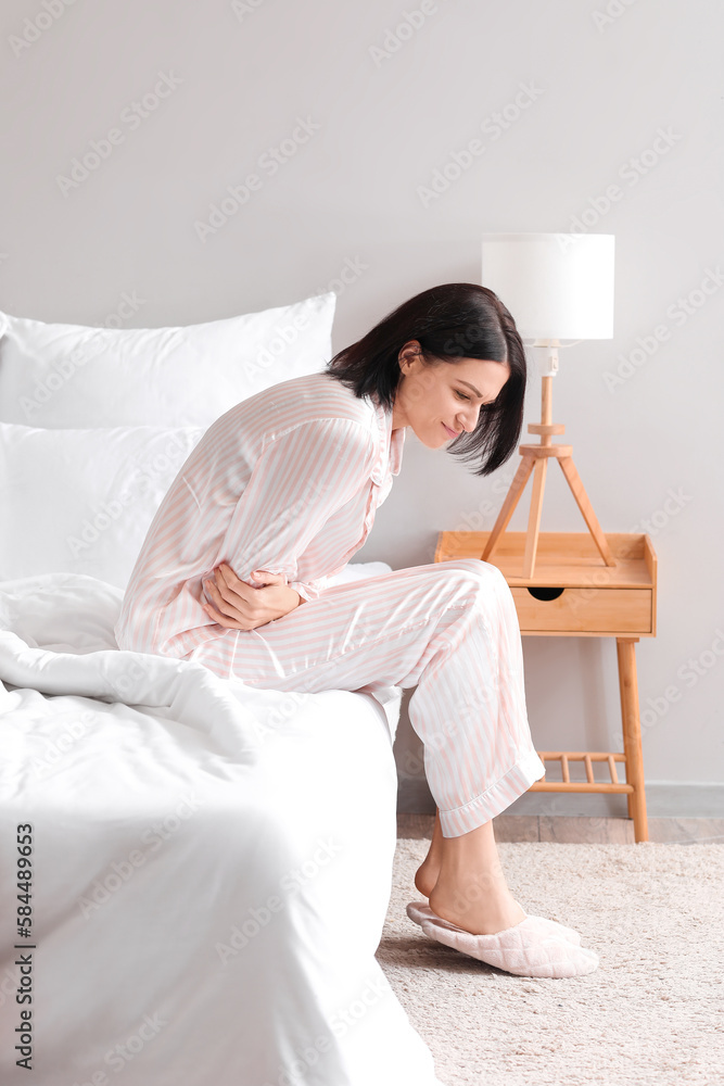 Young woman suffering from menstrual cramps in bedroom Young woman suffering from menstrual cramps in bedroom