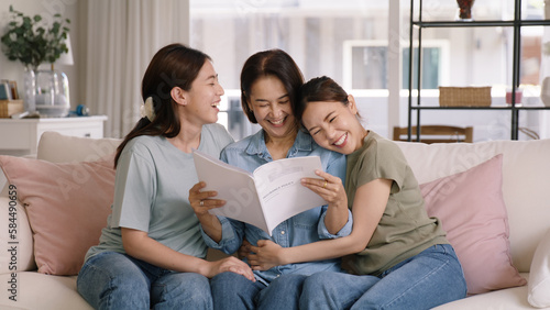 Buy mediclaim health care life insure for older mum. Young adult woman asia people grown up child give gift to middle aged mom reading protect cover saving plan paper smile laugh sitting at sofa home. © ChayTee