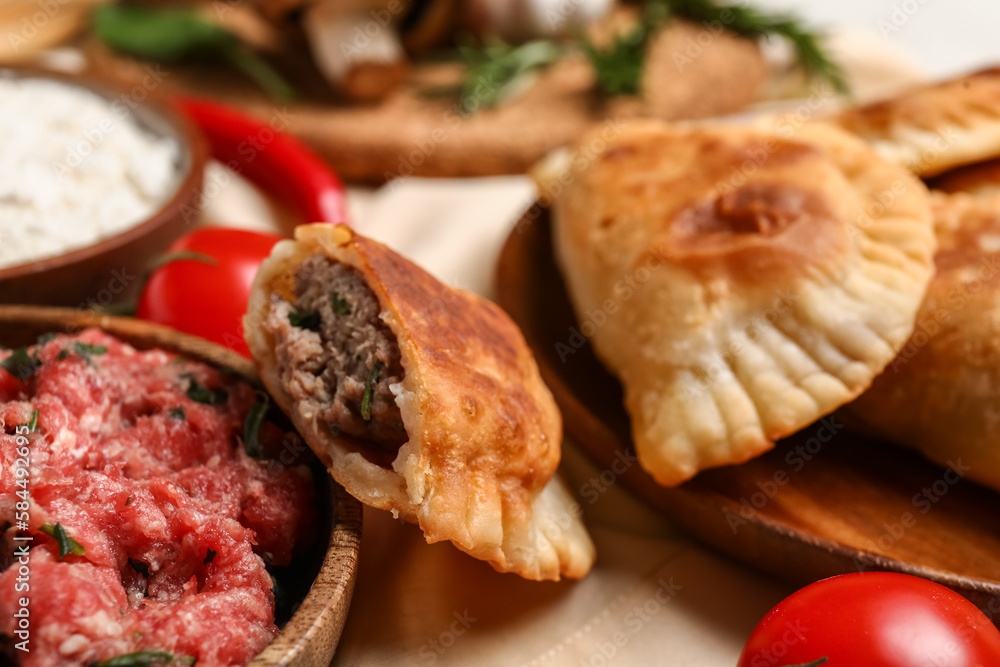 Tasty meat empanadas and ingredients on table, closeup Tasty meat empanadas and ingredients on table, closeup