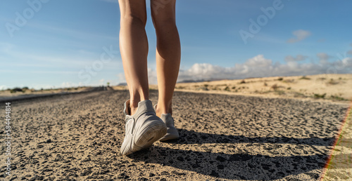 Photo of runner legs running on the street on sporty shoes. Woman fitness workout concept.