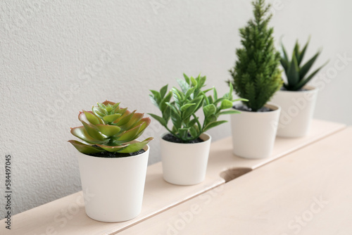 Artificial plants on table near light wall