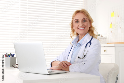 Doctor with laptop and stethoscope at workplace in clinic. Online medicine concept