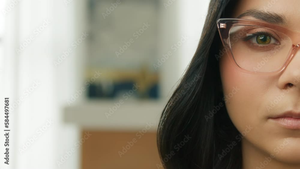 Half Face portrait of young beautiful brunette lady with closed eye in reading eyeglasses. Pretty girl opening eyes and looking straight to camera on copy background. Smart people close up slow motion Half Face portrait of young beautiful brunette lady with closed eye in reading eyeglasses. Pretty girl opening eyes and looking straight to camera on copy background. Smart people close up slow motion