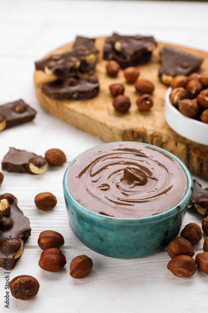 Bowl with tasty paste, chocolate pieces and nuts on white wooden table Bowl with tasty paste, chocolate pieces and nuts on white wooden table