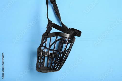 Black plastic dog muzzle on light blue wooden table  top view