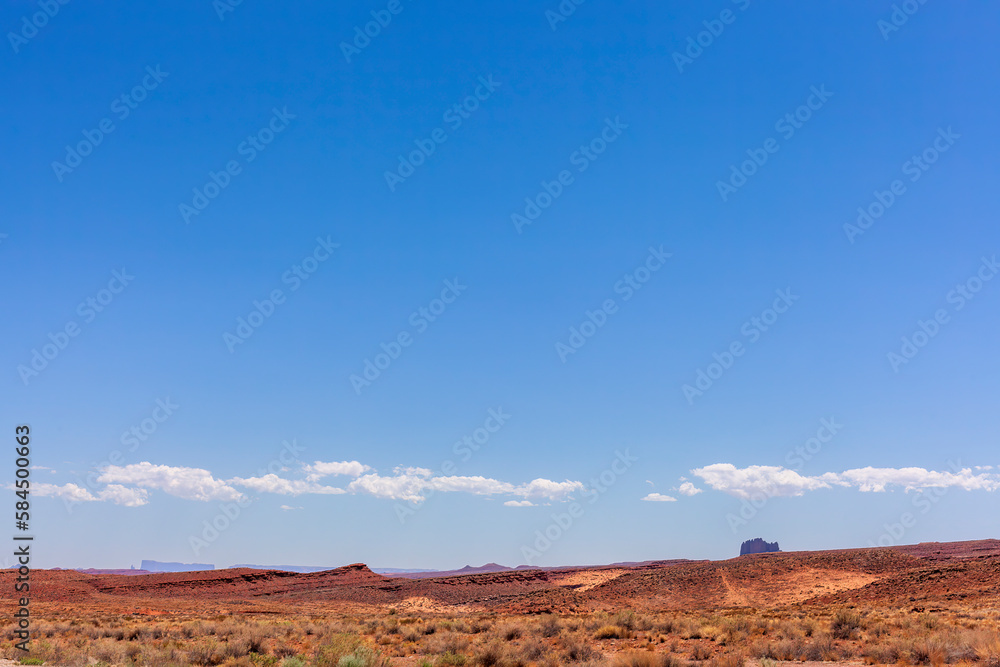 Low horizon photo of the edge of Monument Valley with red rocks and blue sky
