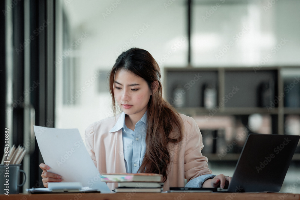 Portrait of a Beautiful businesswoman sitting at a desk and working with a laptop computer. Portrait of a Beautiful businesswoman sitting at a desk and working with a laptop computer.