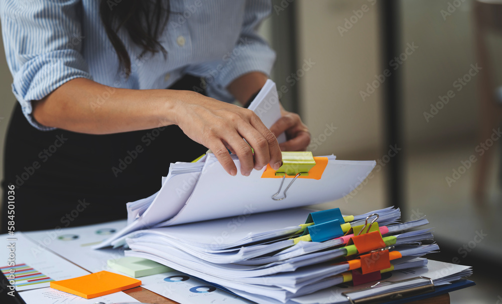 Businesswoman hands working in Stacks of paper files for searching and checking unfinished document achieves on folders papers. - obrazy, fototapety, plakaty 