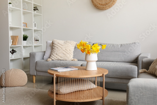 Interior of modern living room with cozy sofa and flower vase on coffee table