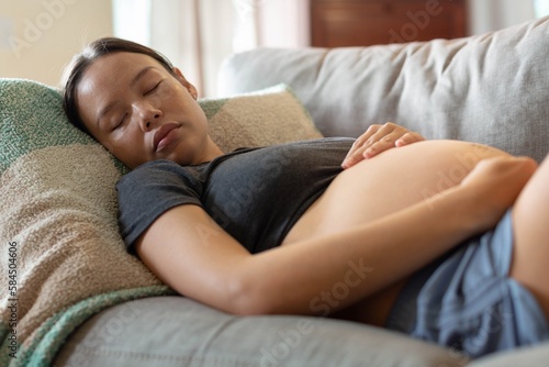 A pregnant woman taking a nap on her couch. Maternity sleep and care.