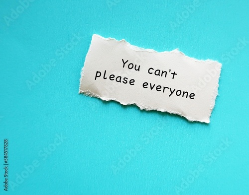 Torn ripped note on blue copy space background with text YOU CAN'T PLEASE EVERYONE - concept of PEOPLE PLEASER who tries hard to make others happy, overly concerned with pleasing others