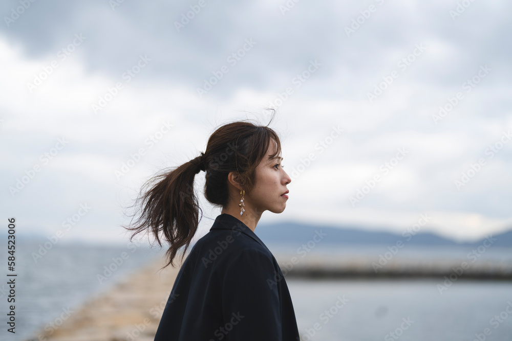 曇りの日の海にいるポニーテールの女性 曇りの日の海にいるポニーテールの女性