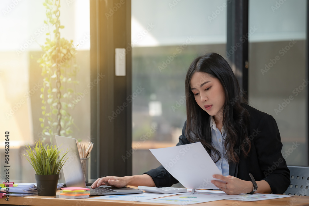 Asian Businesswoman working on a laptop at her desk at the office. Asian Businesswoman working on a laptop at her desk at the office.
