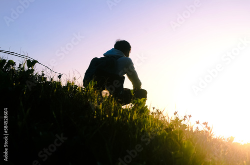 Young man sitting outdoors watching the sunset. Thinking and relaxing concept.