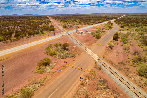 Looking down at asphalt road and railway crossing on the red terrain earth in outback Australia