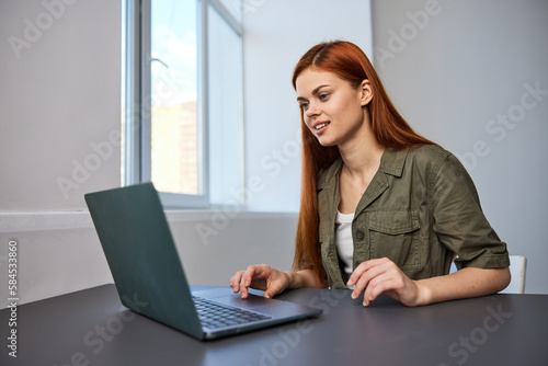 portrait of a happy, joyful woman sitting at a laptop and working in the office © VICHIZH