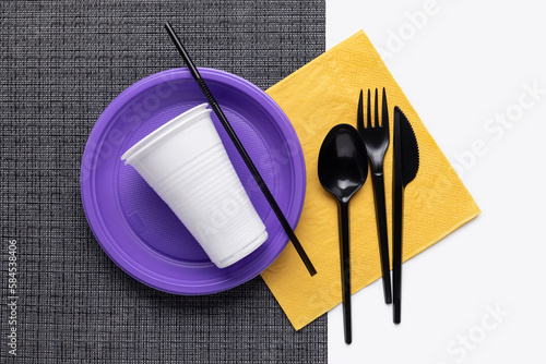 A set of multi-colored plastic utensils on a black and white background, top view.