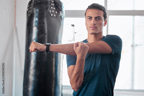 Serious, stretching arm and man in gym ready to start workout, training or exercise. Sports fitness, thinking and young male athlete warm up, stretch arms or prepare for exercising for flexibility.