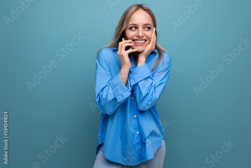 pleasantly surprised cute blonde woman chatting on the phone on a blue bright background