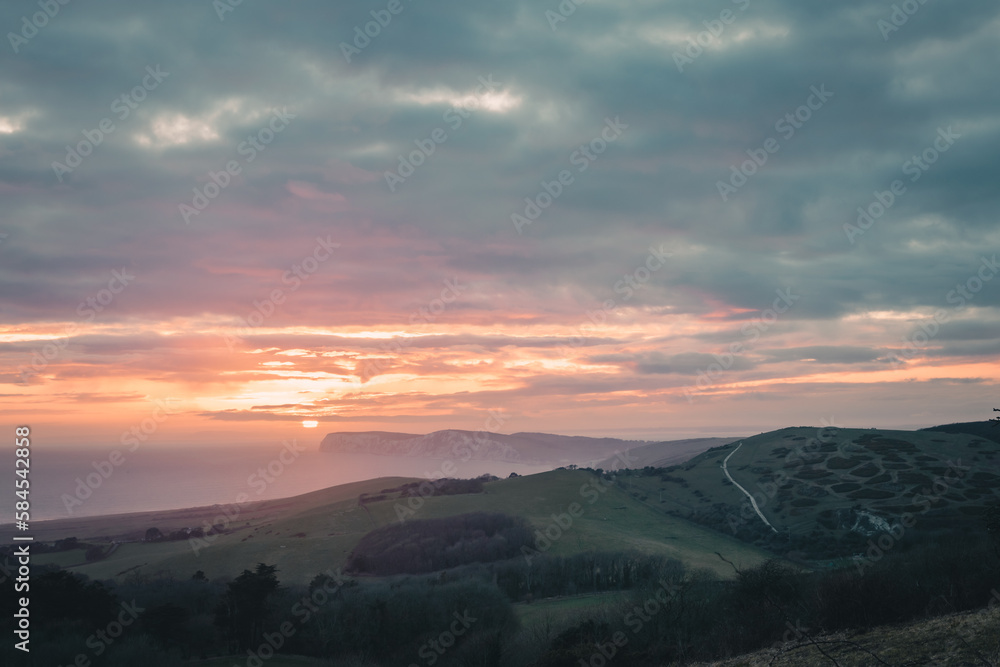 A beautiful sunset landscape with a sea view and mist over the cliffs