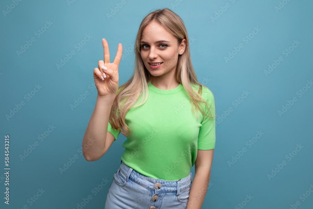 smart smiling girl in casual outfit showing two fingers on blue background smart smiling girl in casual outfit showing two fingers on blue background