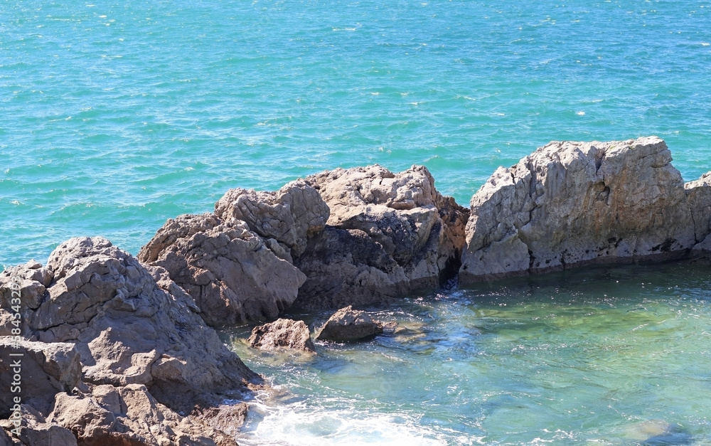 Rocks in the sea forming a barrier near the beach in summer