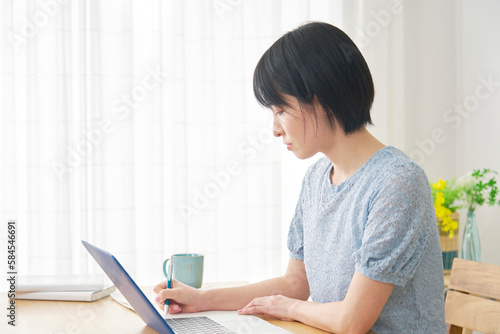 自宅でノートパソコンを使って勉強する女性