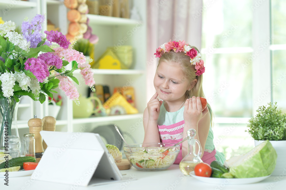 little girl making dinner on kitchen table with tablet at home little girl making dinner on kitchen table with tablet at home