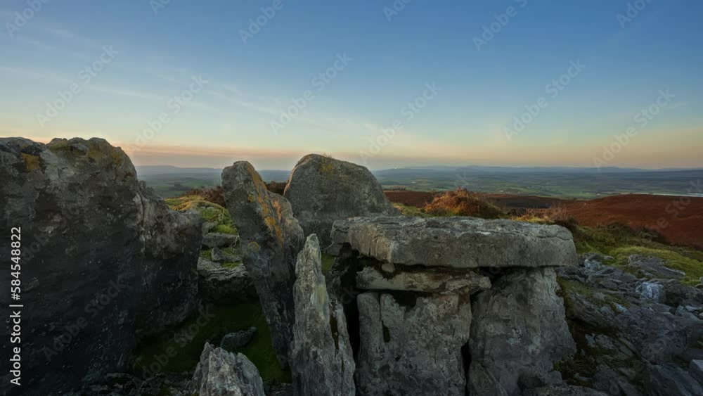 Panorama motion timelapse of rural nature landscape with ruins of prehistoric passage tomb stone ruin in the foreground during sunset viewed from Carrowkeel in county Sligo in Ireland. Panorama motion timelapse of rural nature landscape with ruins of prehistoric passage tomb stone ruin in the foreground during sunset viewed from Carrowkeel in county Sligo in Ireland.