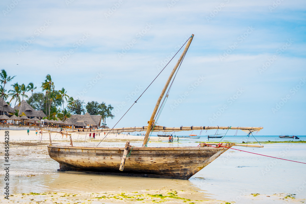 Near a tropical island, a traditional Zanzibar fishing boat lies in clear water close to the beach, perfect for summer travel and fishing boats Near a tropical island, a traditional Zanzibar fishing boat lies in clear water close to the beach, perfect for summer travel and fishing boats