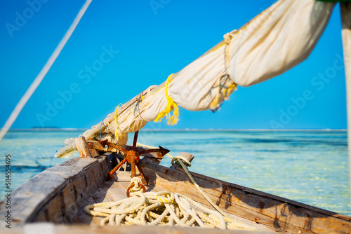 Near a tropical island, a traditional Zanzibar fishing boat lies in clear water close to the beach, perfect for summer travel and fishing boats