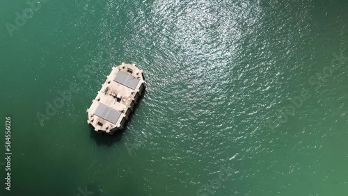 Aerial Birdseye view above Fawley power station cooling water outlet surrounded by shimmering sunlit emerald ocean photo