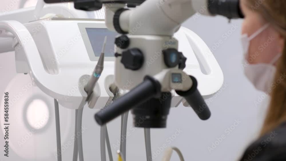 Modern dental clinic with microscope tool for treatment patients. Doctor hand in protective glove putting medical microscope. Man dentist uses microscope. Medical equipment, dental clinic High quality Modern dental clinic with microscope tool for treatment patients. Doctor hand in protective glove putting medical microscope. Man dentist uses microscope. Medical equipment, dental clinic High quality