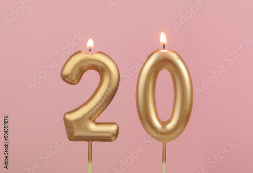 Burning golden birthday candles on pink background, number 20 photo